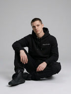 Model sitting while wearing Signature Hoodie Unisex